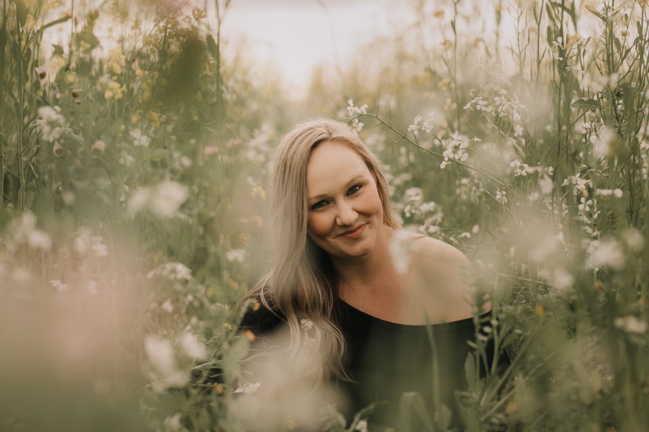 Robin Baglietto smiling sitting in field landscape.